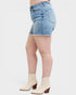 Person wearing light blue denim shorts and white boots on a plain background