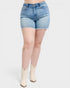 Person wearing light blue denim shorts and white boots on a white background