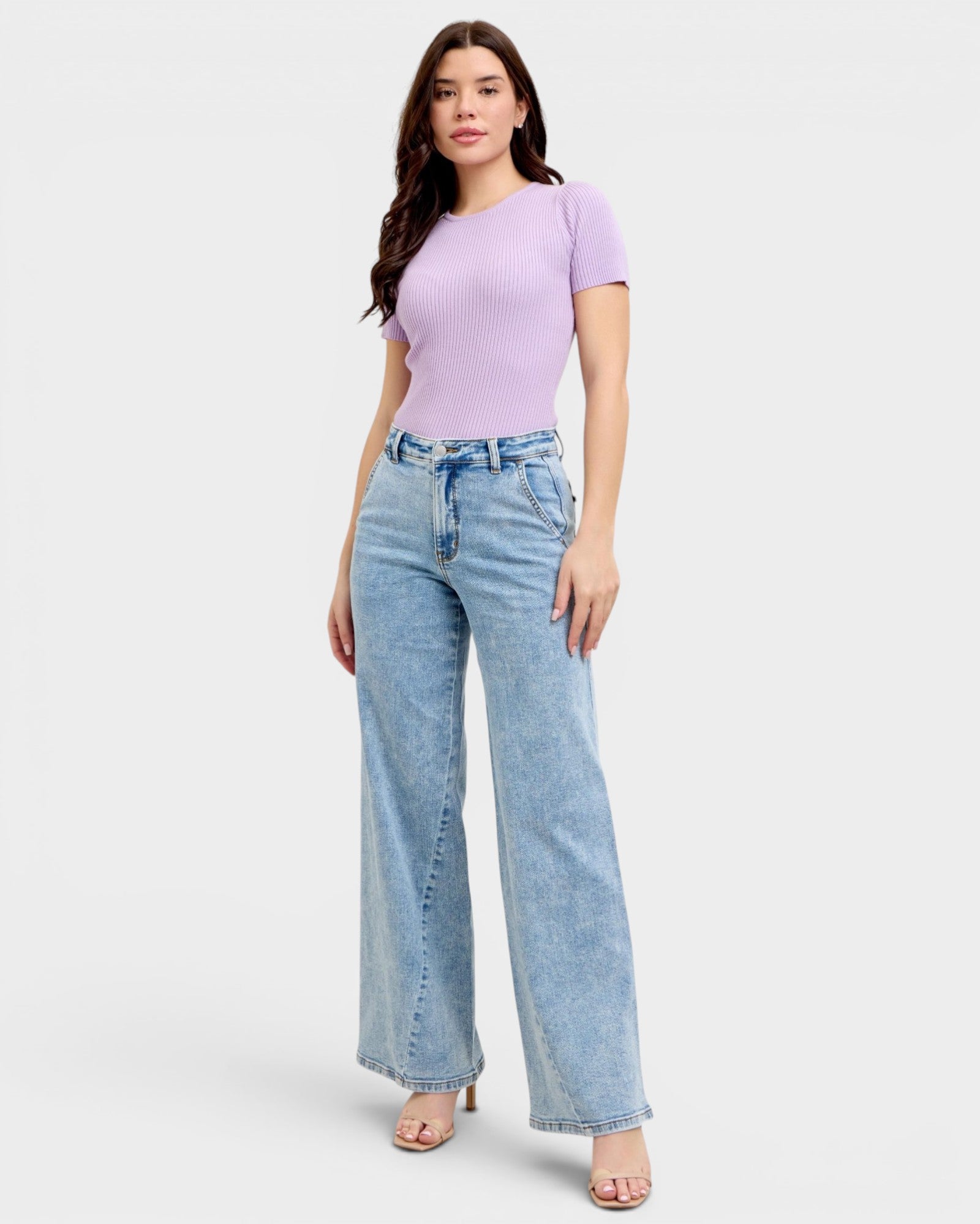 Woman wearing a light purple top and blue jeans on a white background