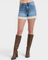 Person wearing denim shorts with white trim and brown knee-high boots on a white background
