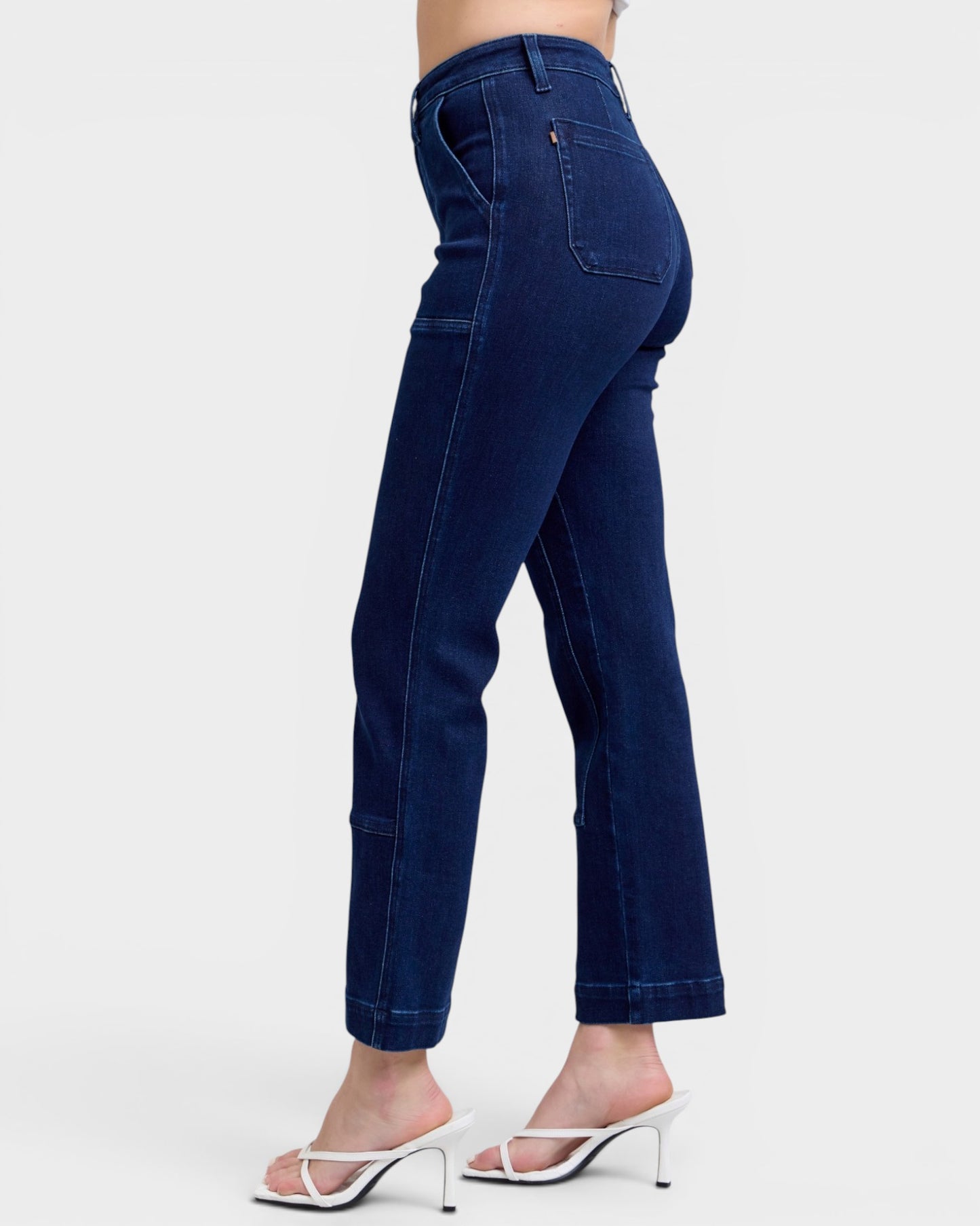 Navy blue jeans worn by a person on a white background