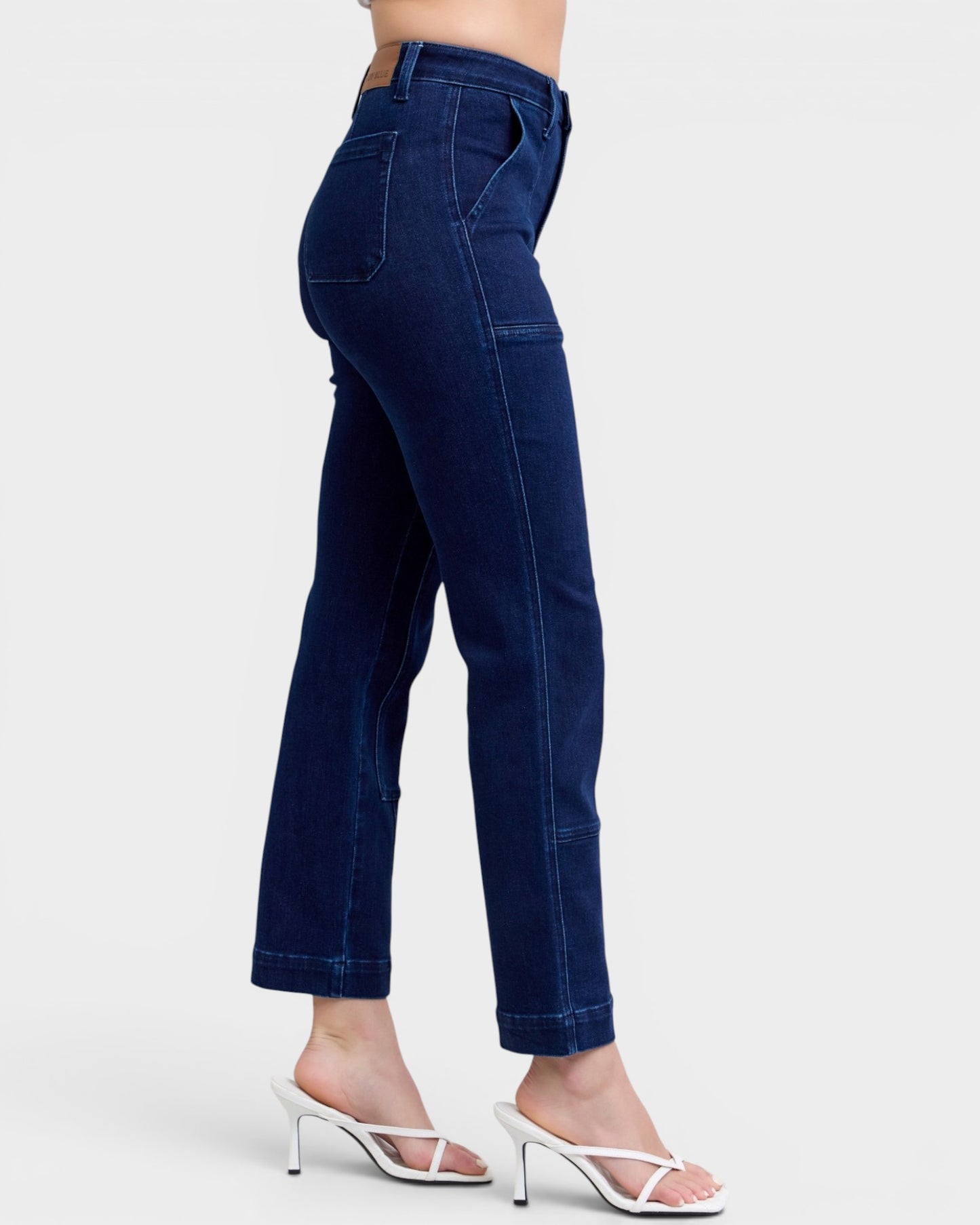 Navy blue jeans worn by a person on a white background