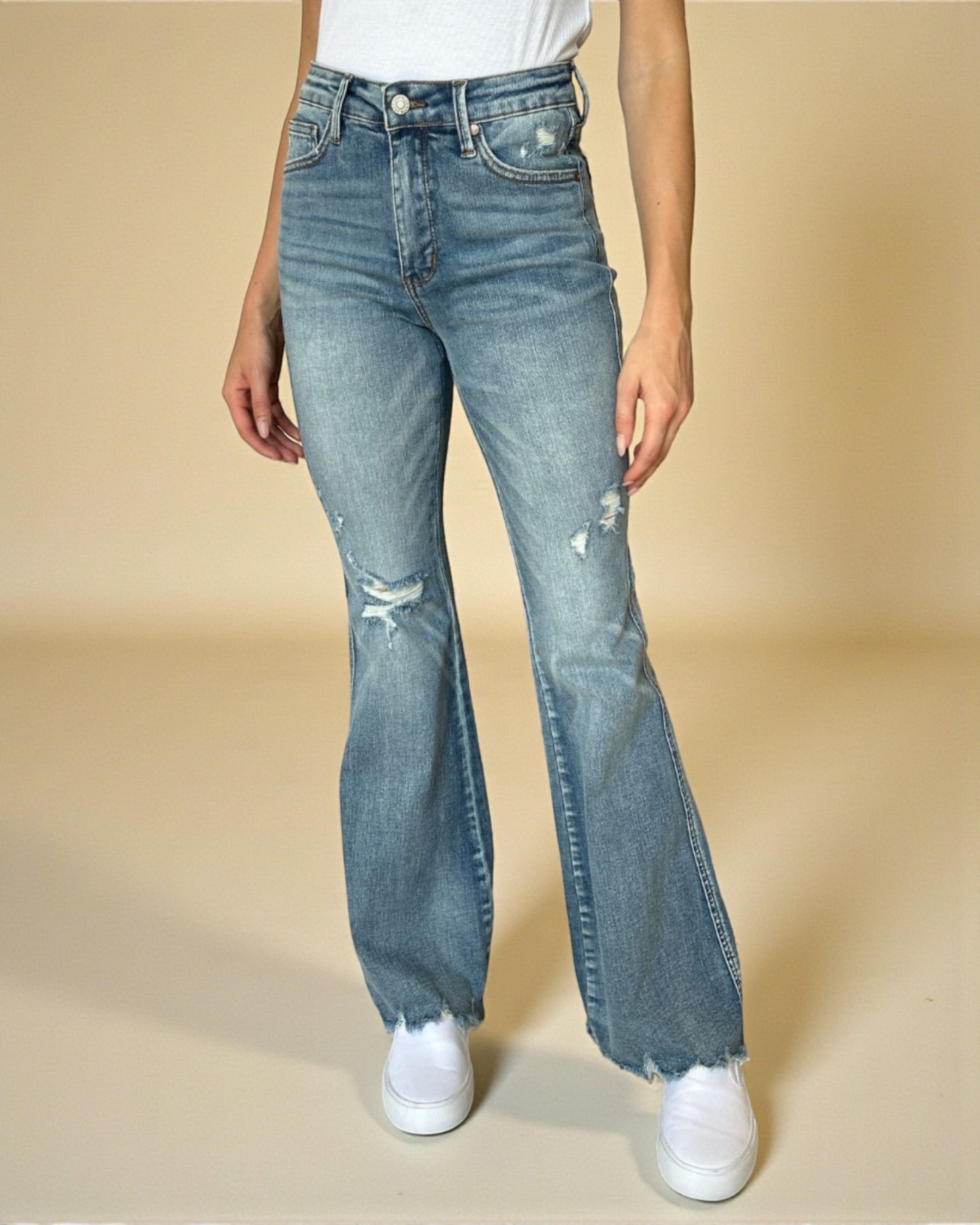 Person wearing blue flared jeans on a beige background