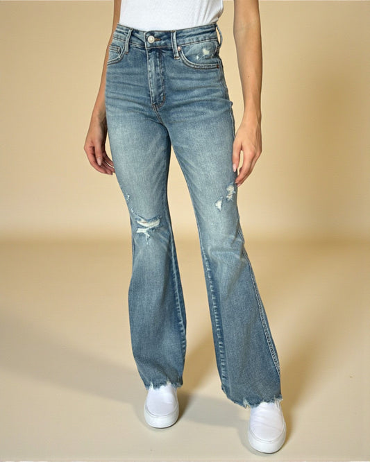 Person wearing blue flared jeans on a beige background