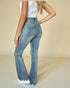 Person wearing light blue flared jeans on a beige background
