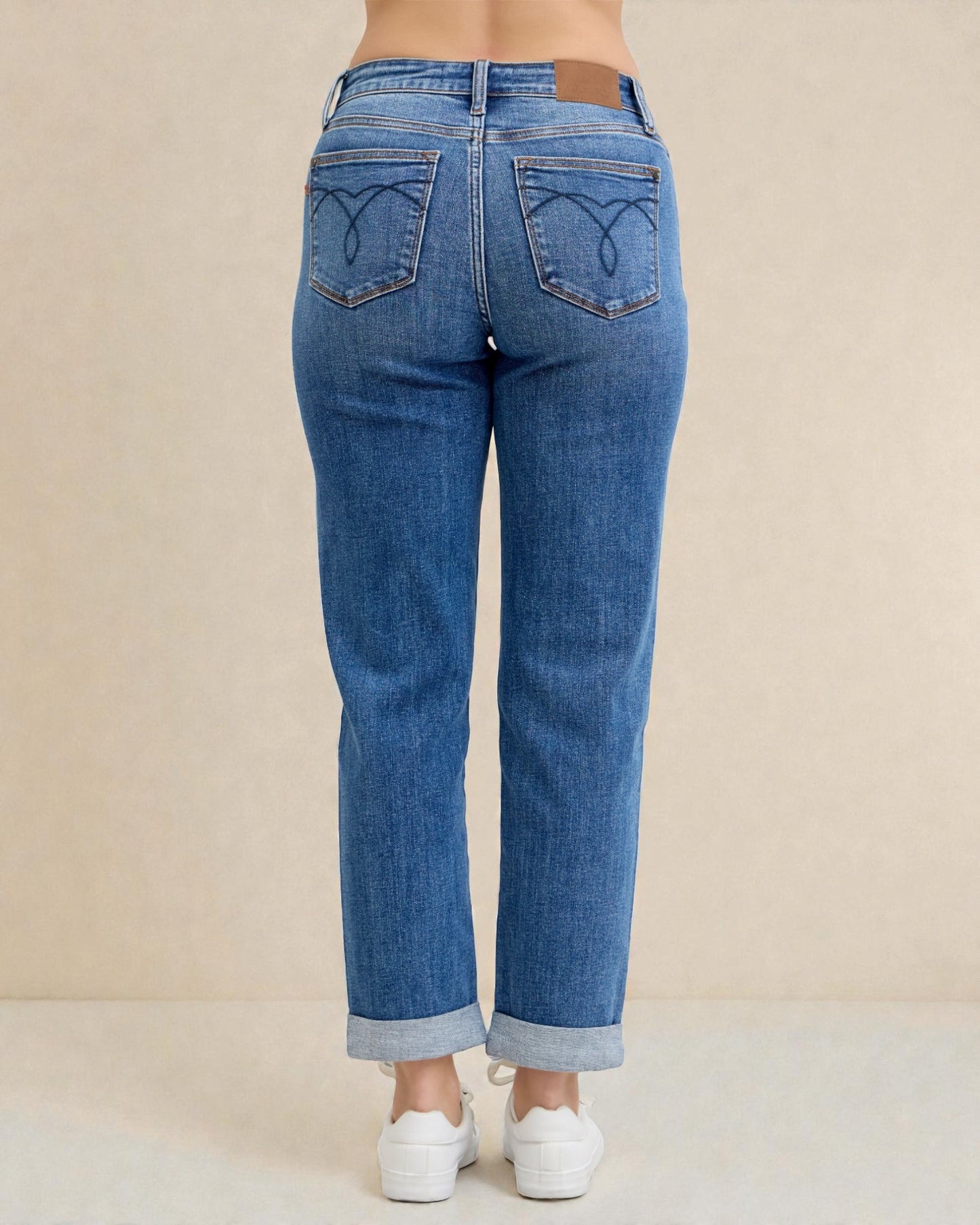 Blue jeans worn by a person on a beige background