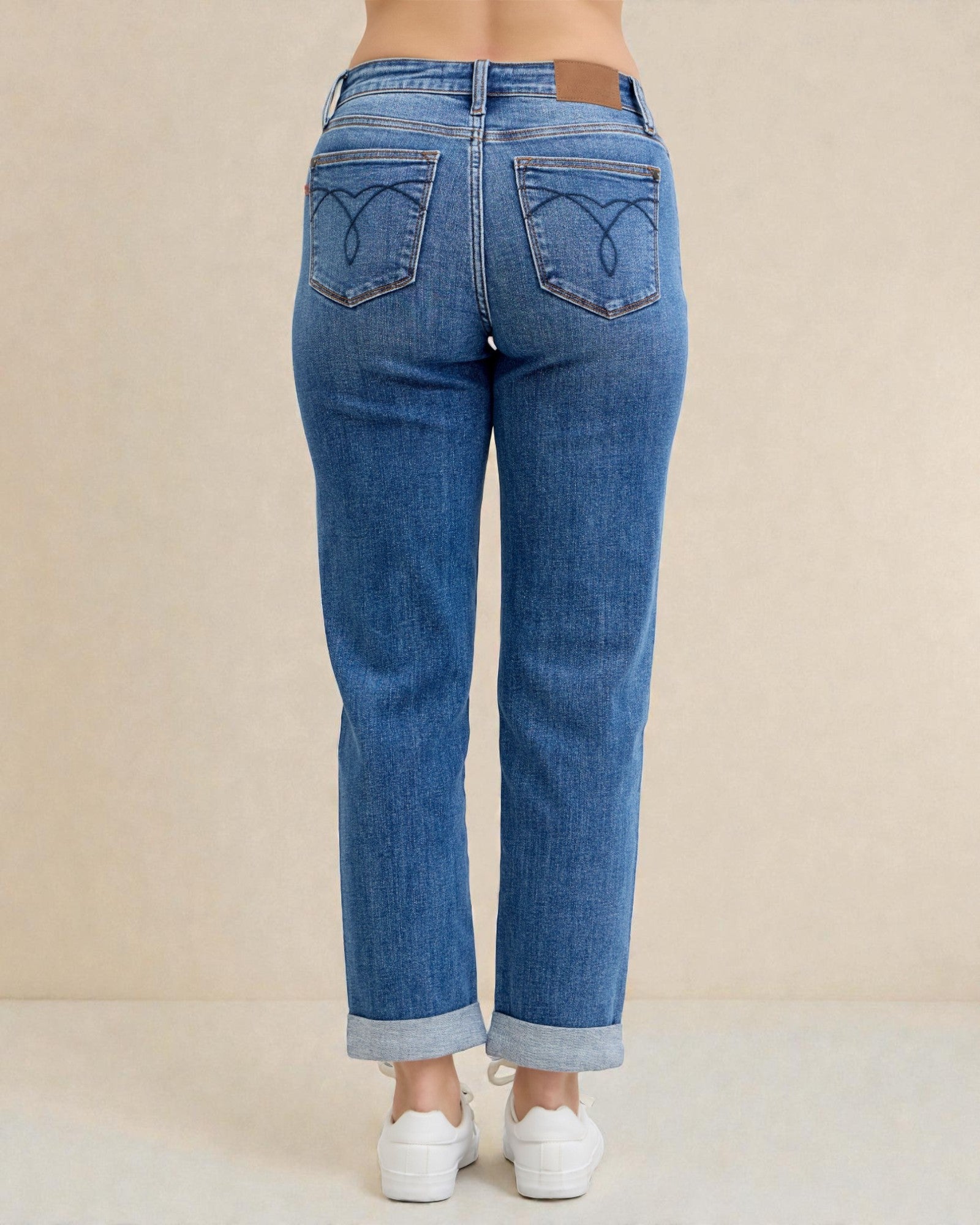 Blue jeans worn by a person on a beige background