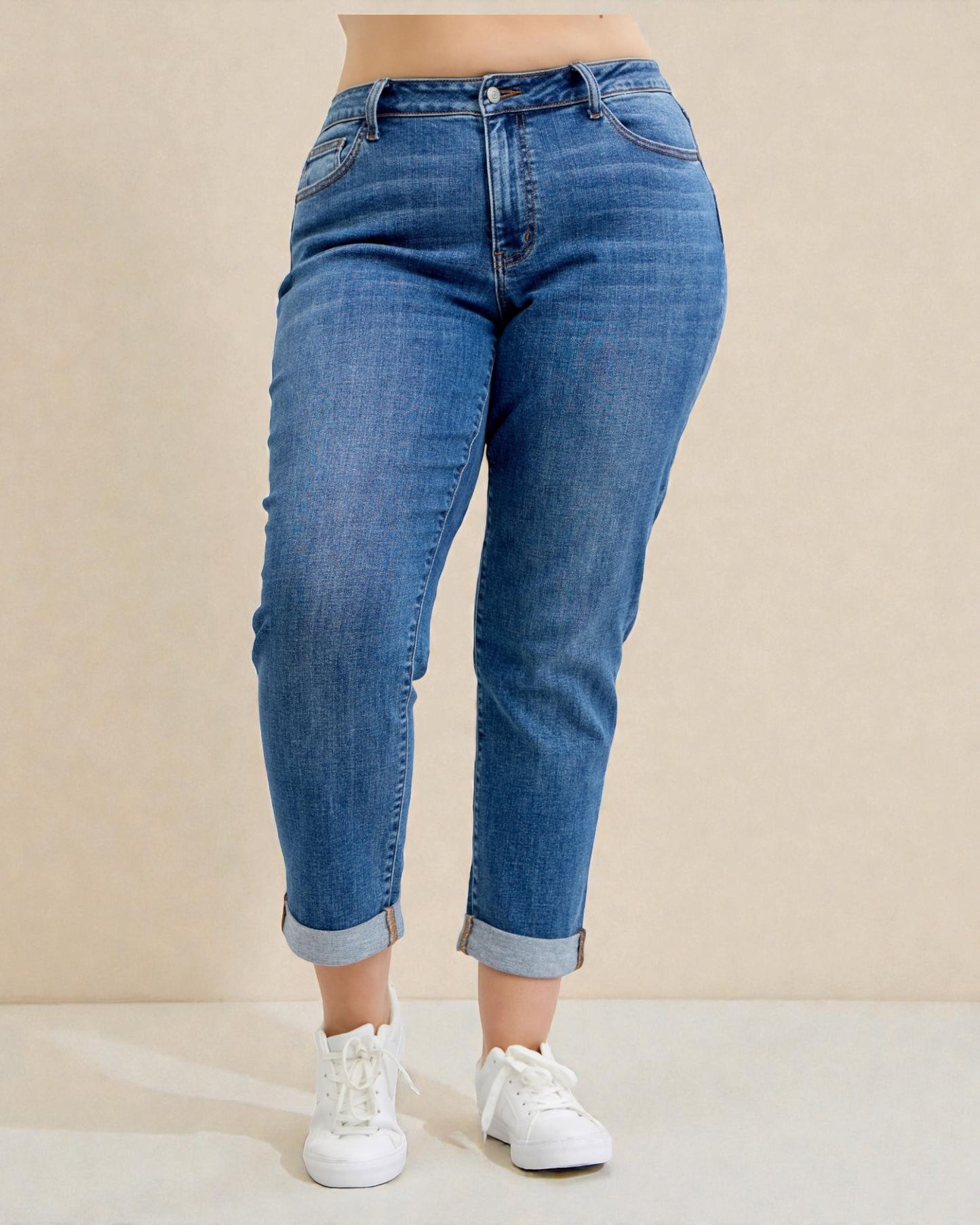 Person wearing blue jeans and white sneakers on a beige background