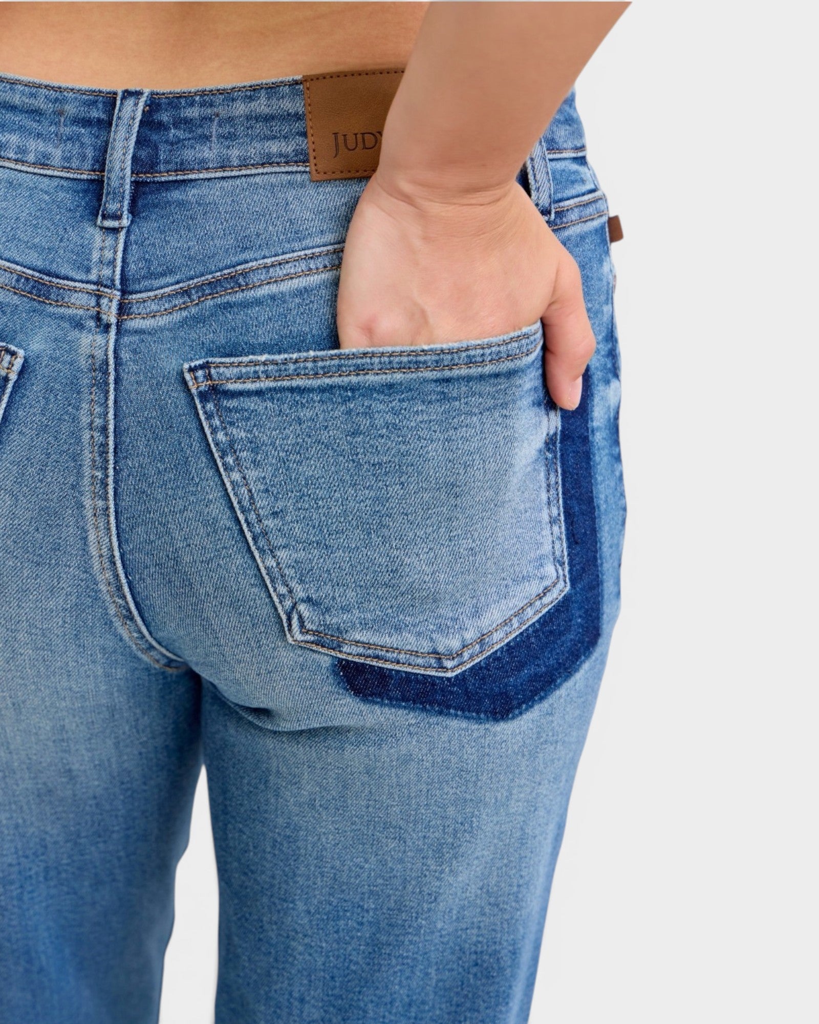 Close-up of blue jeans with a visible brand label on a white background