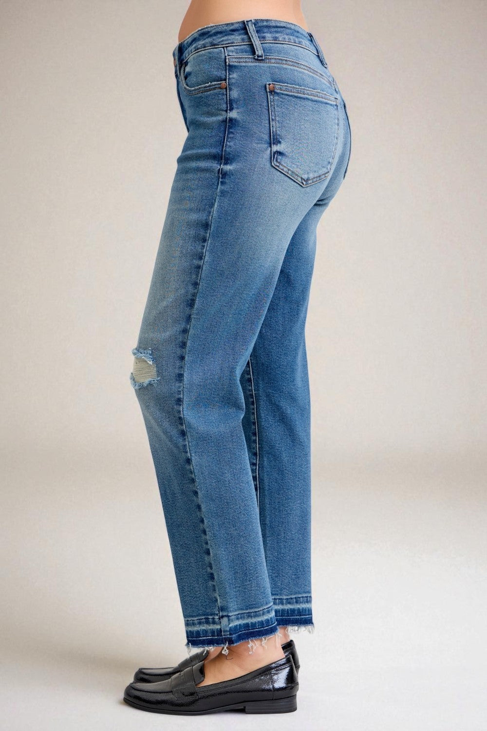 Blue jeans worn by a person on a plain background