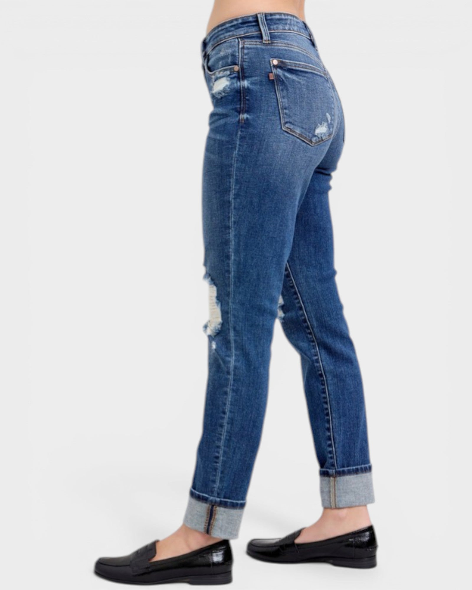 Blue jeans with a slight distressed look worn by a person on a white background