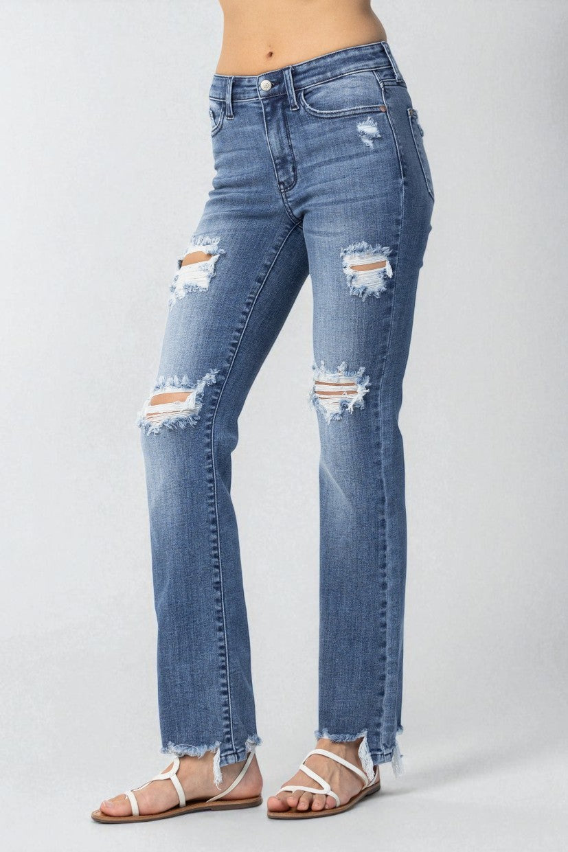 Distressed blue jeans worn by a person on a plain background