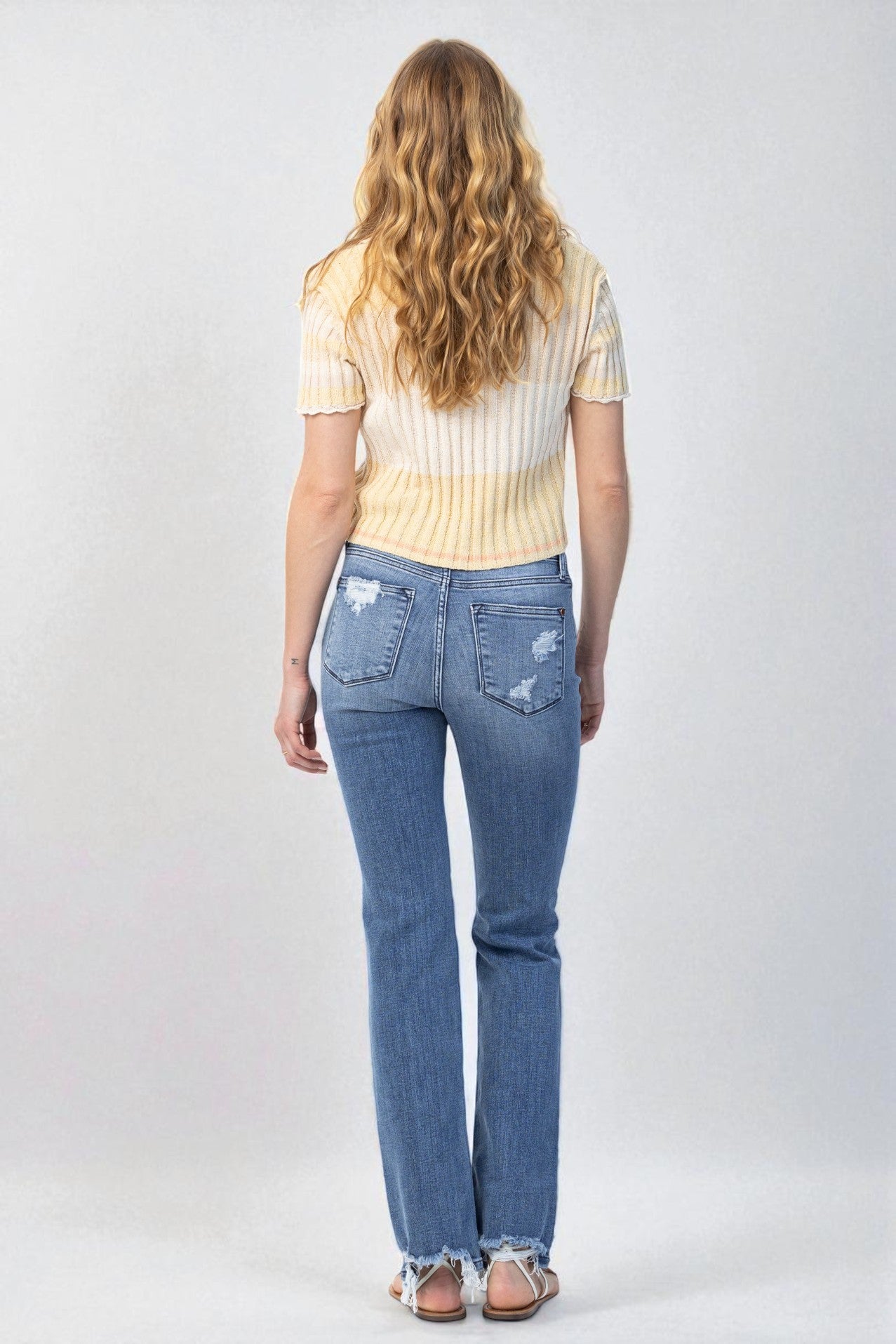 Person wearing blue jeans and a striped shirt on a white background
