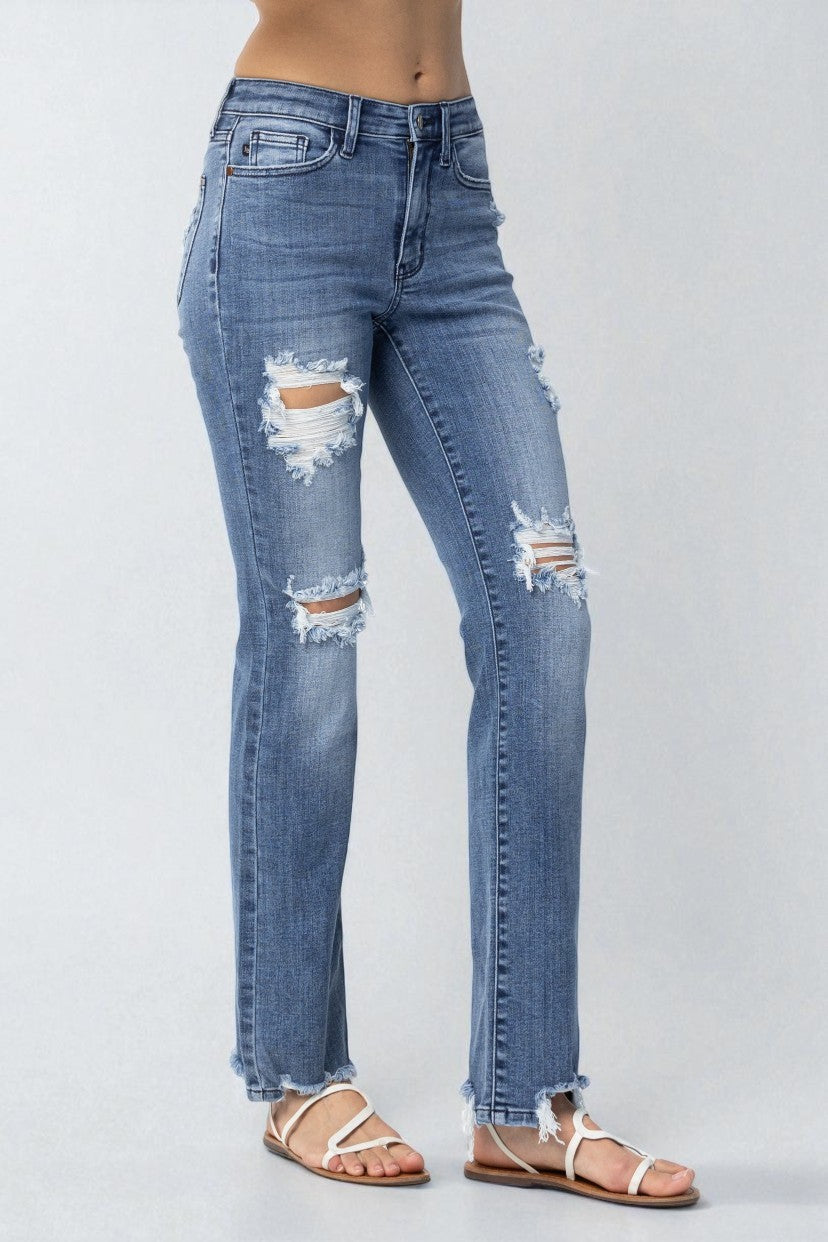 Ripped blue jeans worn by a person on a white background