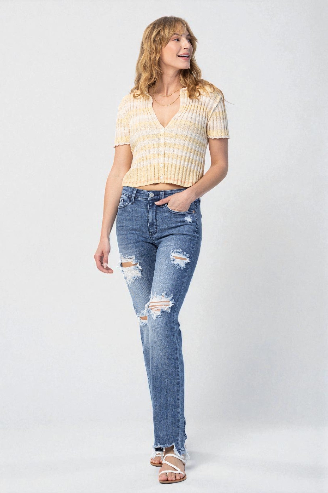 Woman wearing a yellow striped shirt and blue jeans on a white background