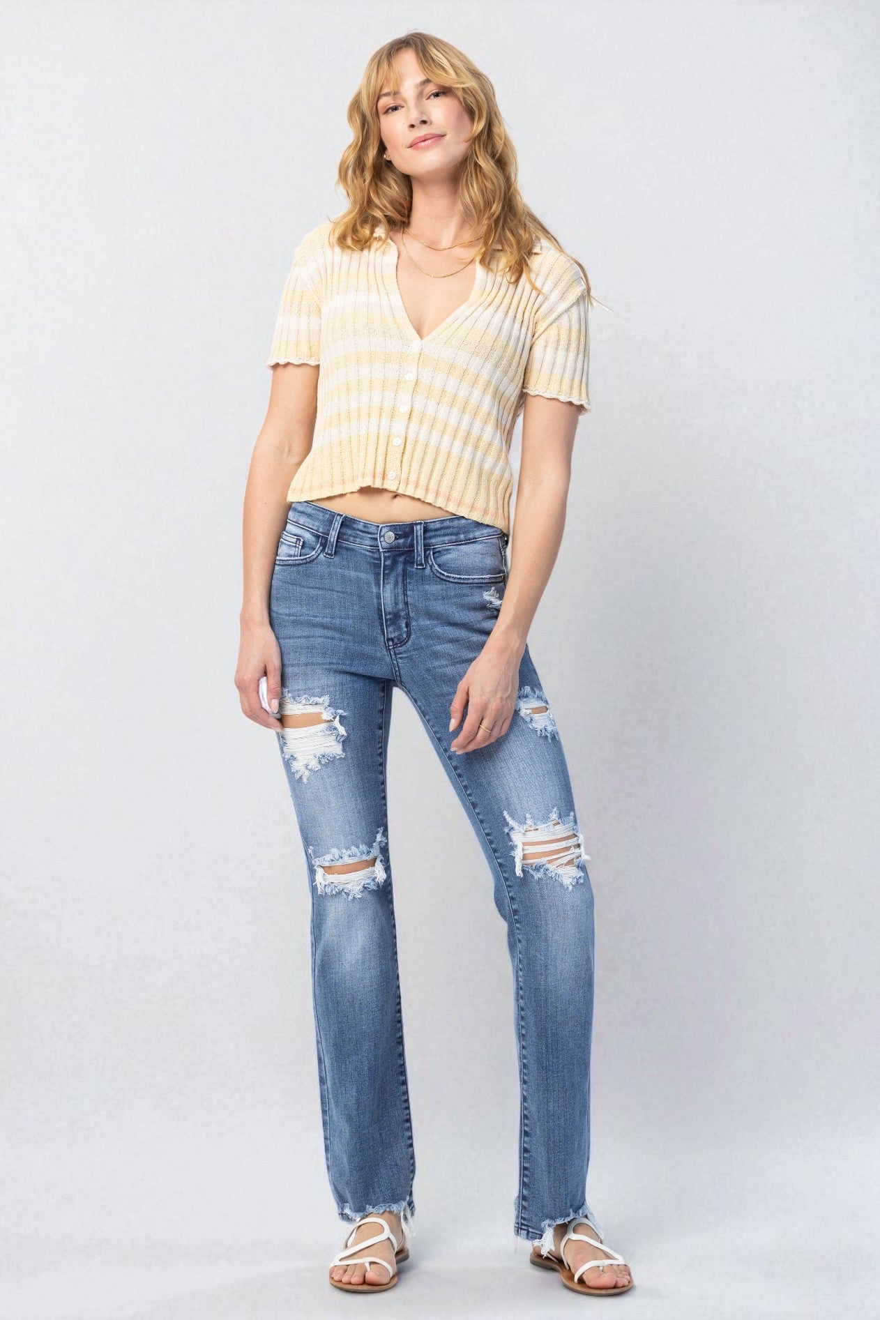 Woman wearing a yellow striped shirt and blue jeans on a white background