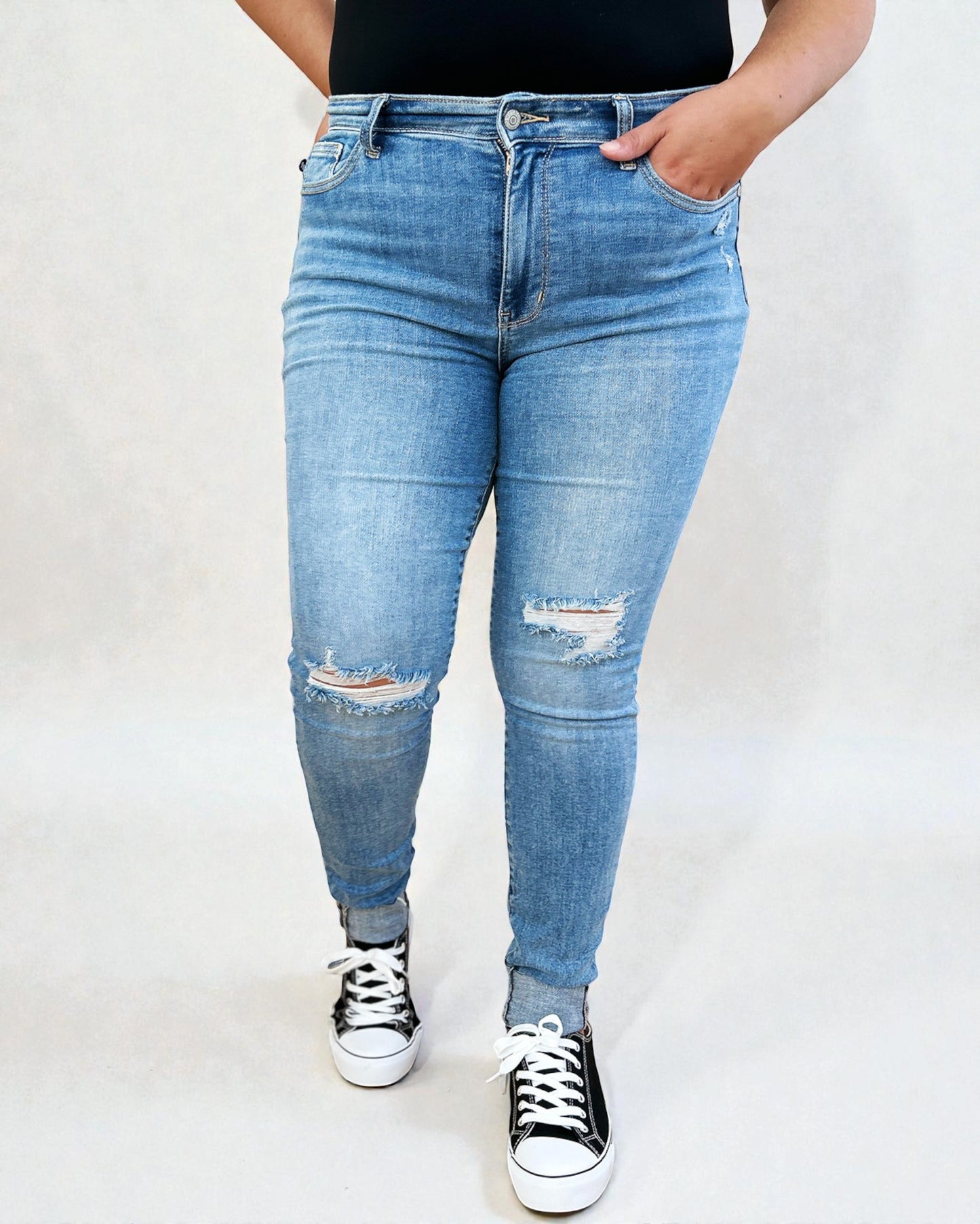 Person wearing blue jeans with slight distressing on a white background