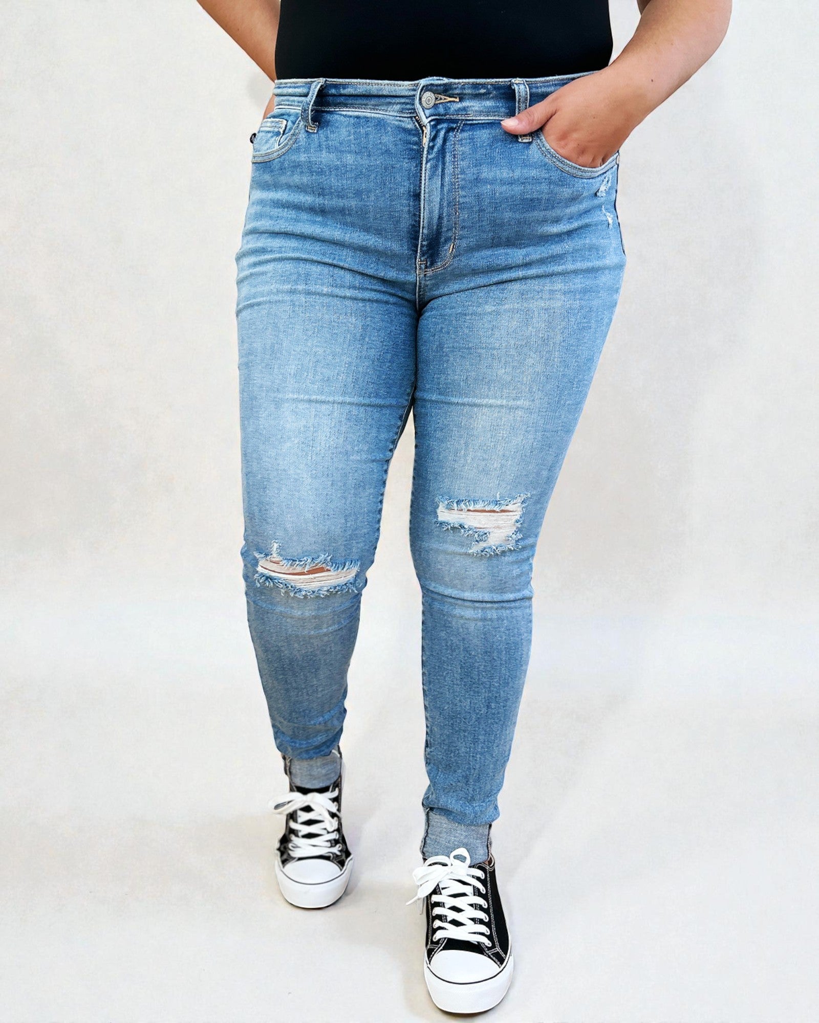 Person wearing blue jeans with slight distressing on a white background
