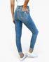 A person wearing blue high-waisted skinny jeans with distressed details and cuffed hems, paired with white sneakers, shown from a rear three-quarter angle against a plain white background.