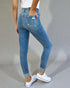 Person wearing blue jeans and white sneakers on a gray background