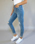 Person wearing blue jeans and white sneakers on a plain background