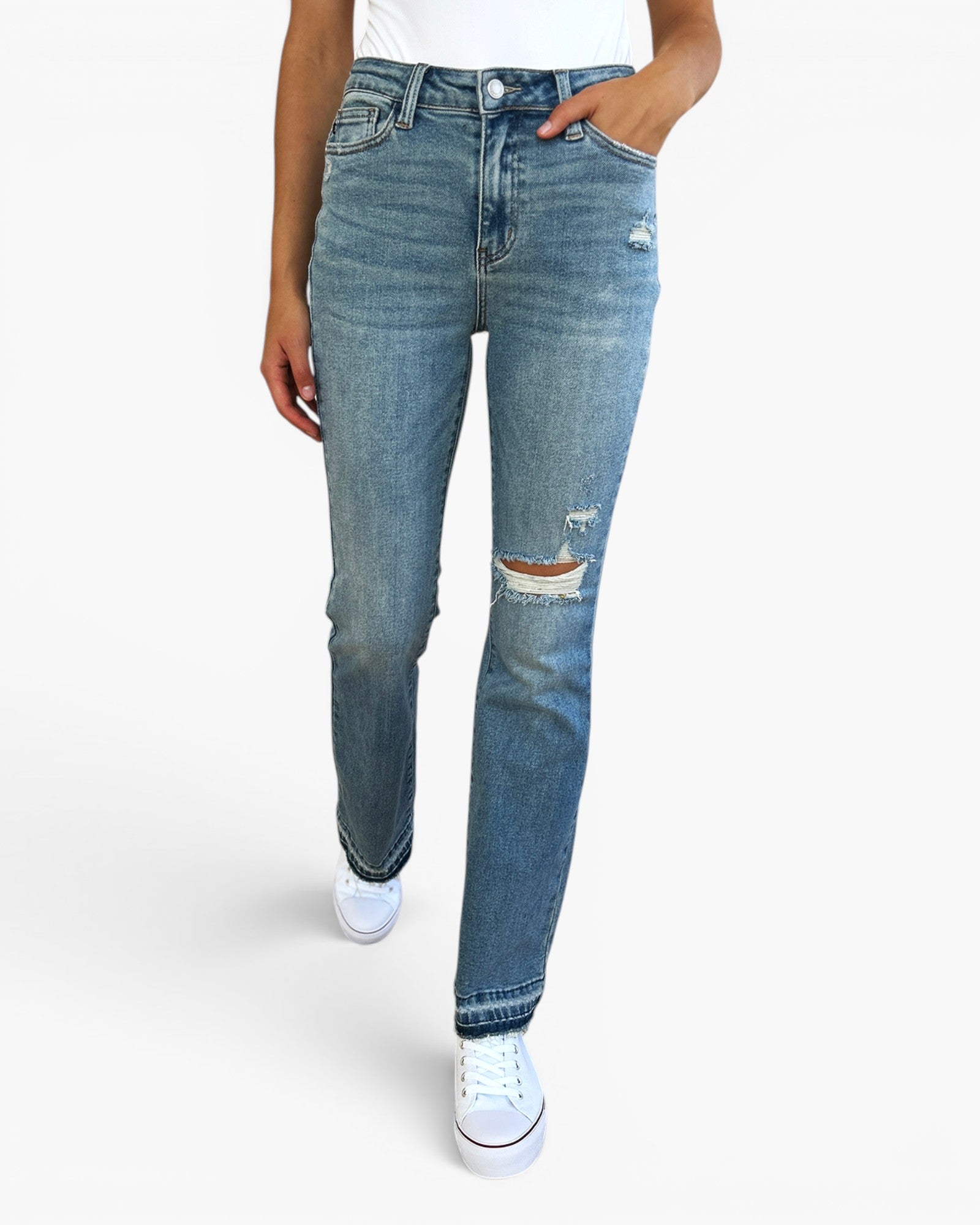 A person wearing light blue distressed denim jeans with a straight-to-slightly-relaxed leg, paired with a white top and white sneakers, shown against a plain light gray studio background.