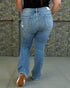 Person wearing blue jeans with a patterned wall in the background
