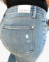 Close-up back view of a person wearing light-wash blue denim jeans with a visible JUDY BLUE waistband label and a distressed detail on the back pocket.