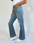 Person wearing light blue distressed jeans and white sneakers on a plain background
