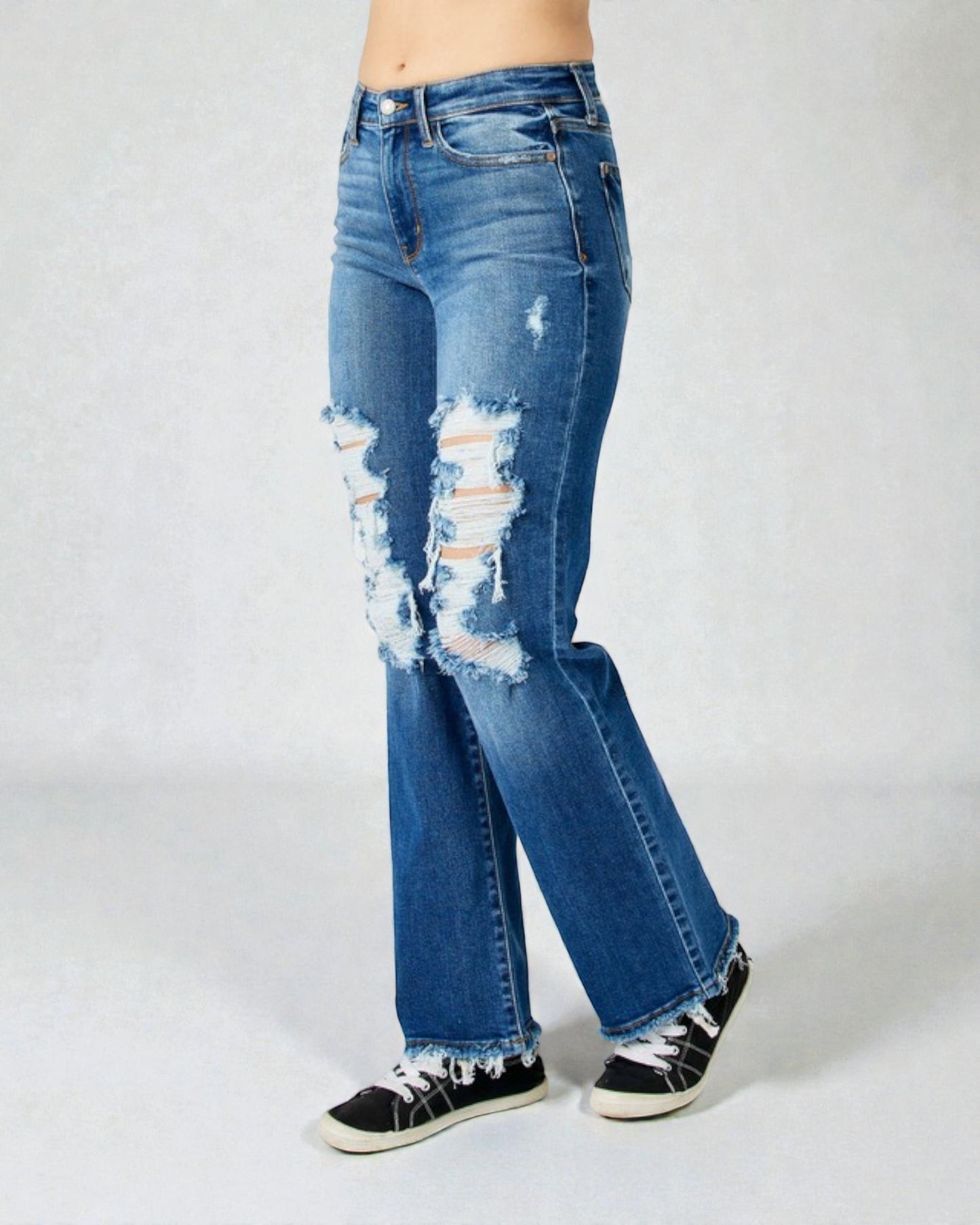 Distressed blue jeans worn by a person on a white background