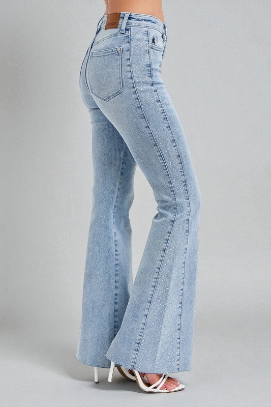 Light blue flared jeans worn by a person on a gray background