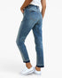 A person wearing blue denim jeans with a straight-to-ripped leg, shown from the back and side against a clean white studio background. The model is also wearing a white top and white sneakers.