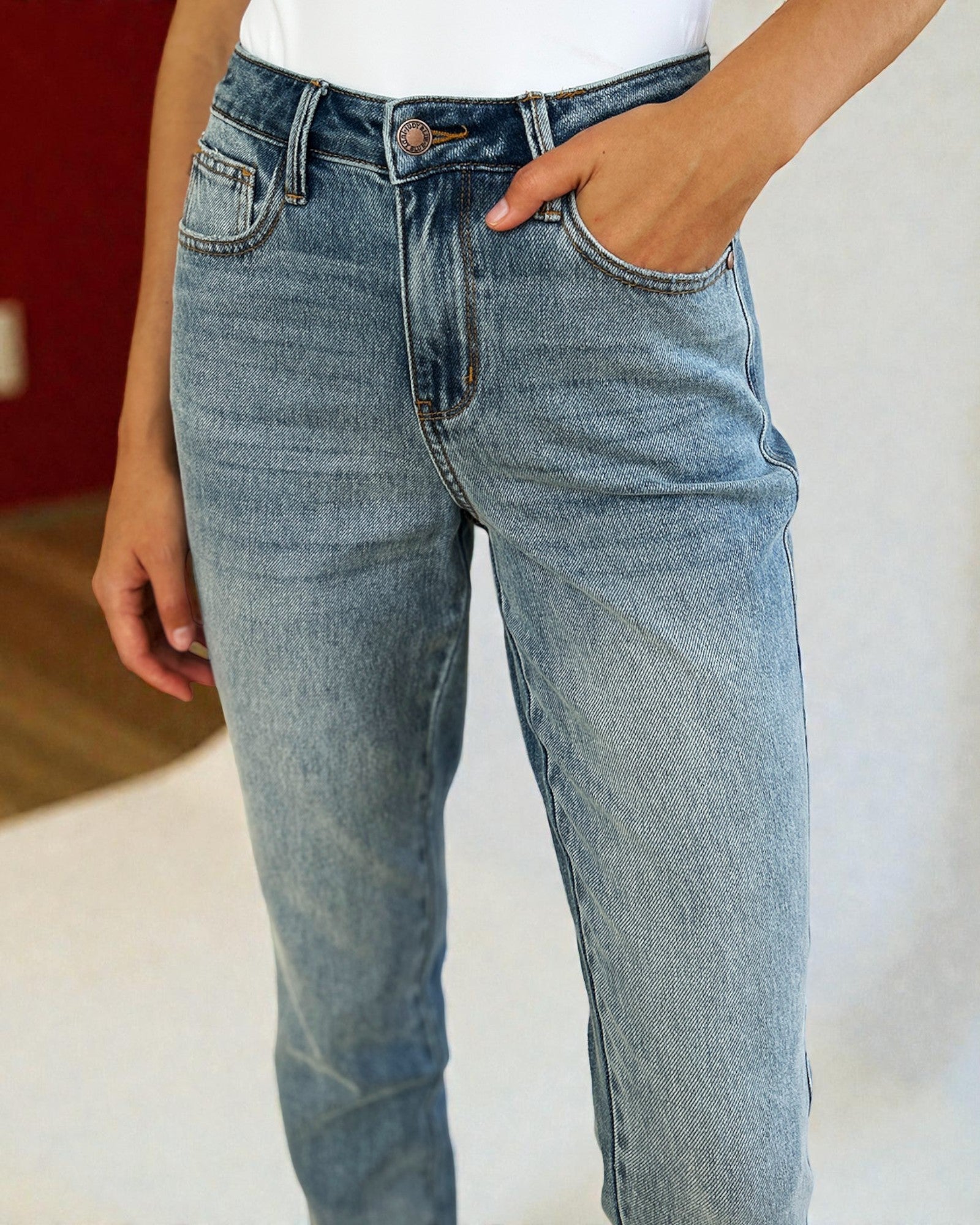 Person wearing light blue jeans with a plain background
