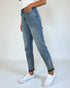Person wearing light blue jeans and white sneakers on a plain background