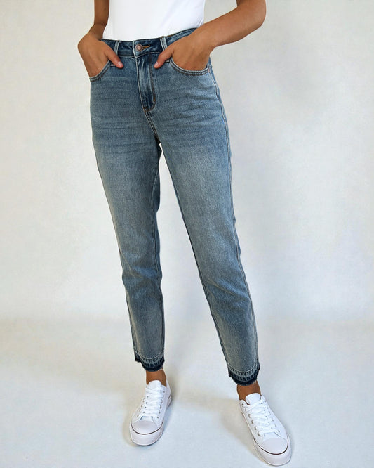 Person wearing blue jeans and white sneakers on a plain background