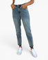 A person wearing light blue high-waisted slim-fit jeans with a faded wash, paired with a white top and white sneakers, shown from the waist down on a light gray studio background.