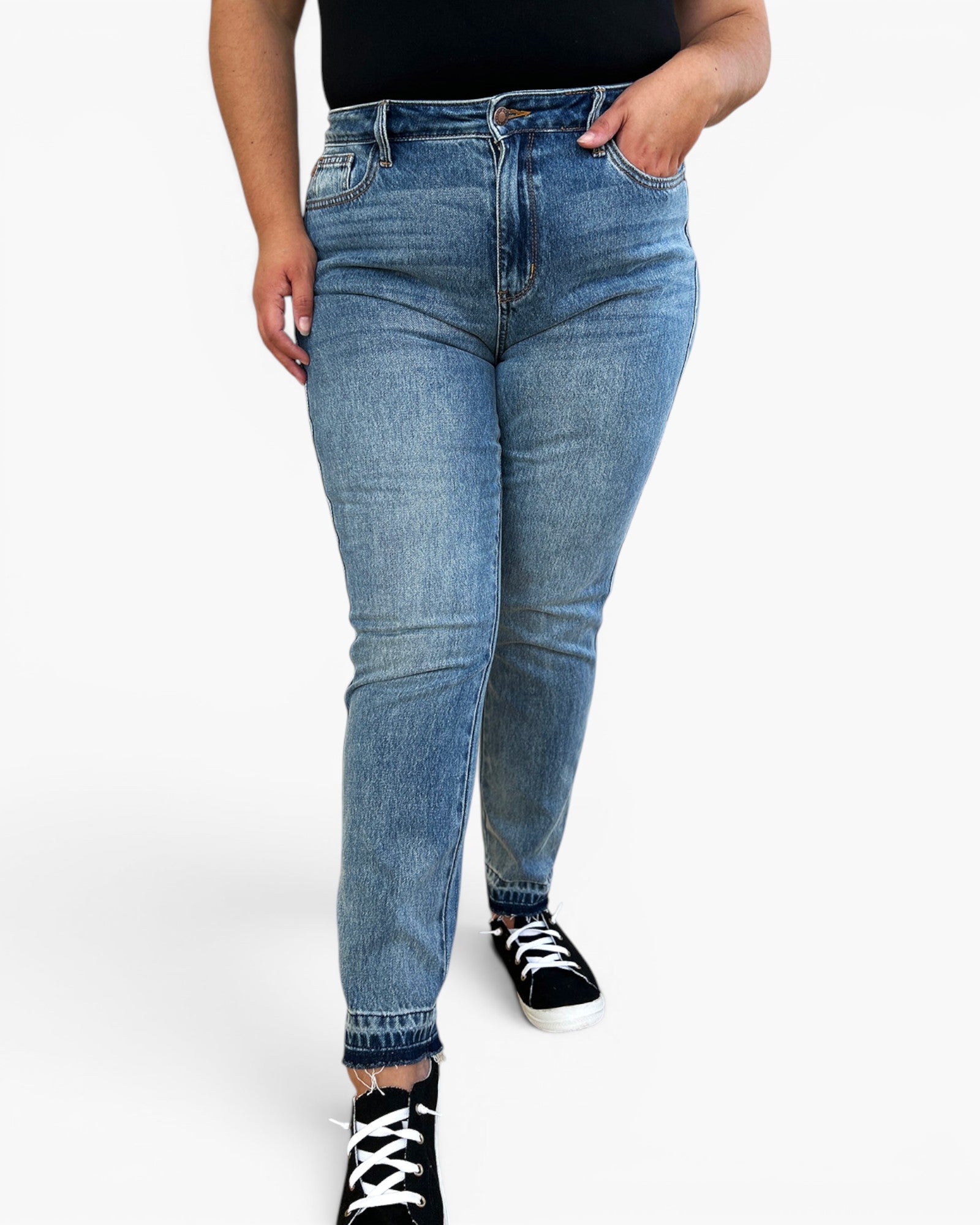 A person wearing light blue slim-fit denim jeans with black sneakers, shown from the waist down against a plain white studio background.