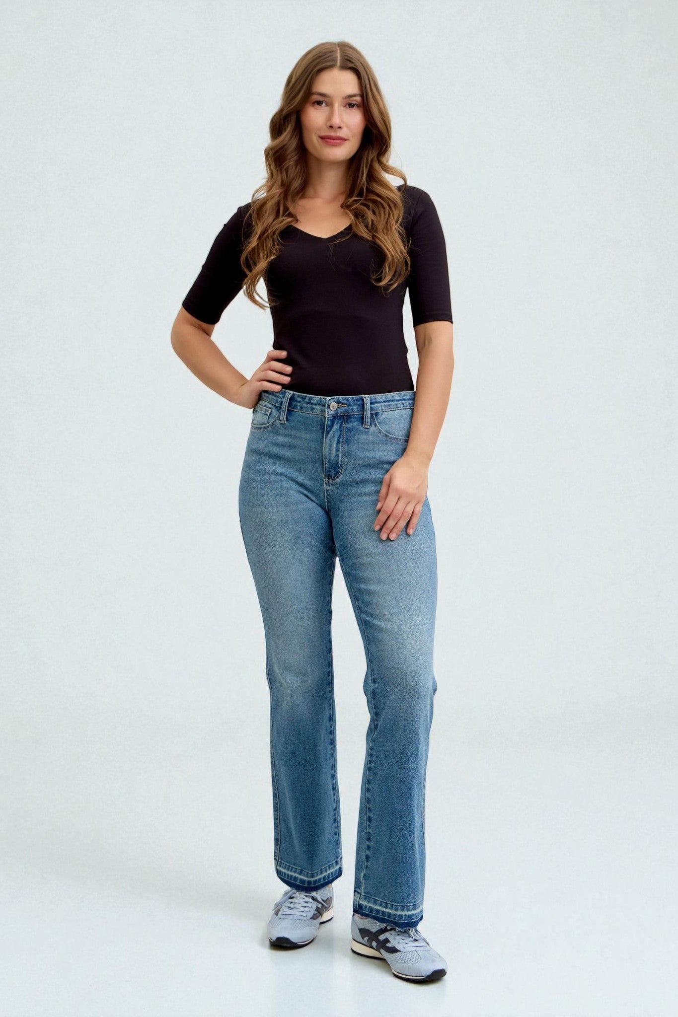 Woman wearing a black top and blue jeans on a white background