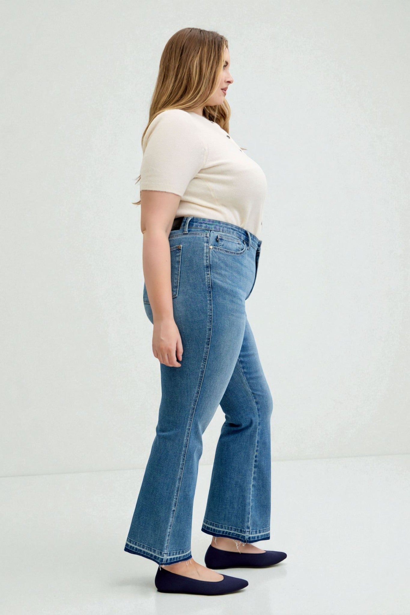 Woman wearing blue jeans and a white top on a white background