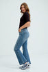 Woman wearing blue jeans and a black top on a white background