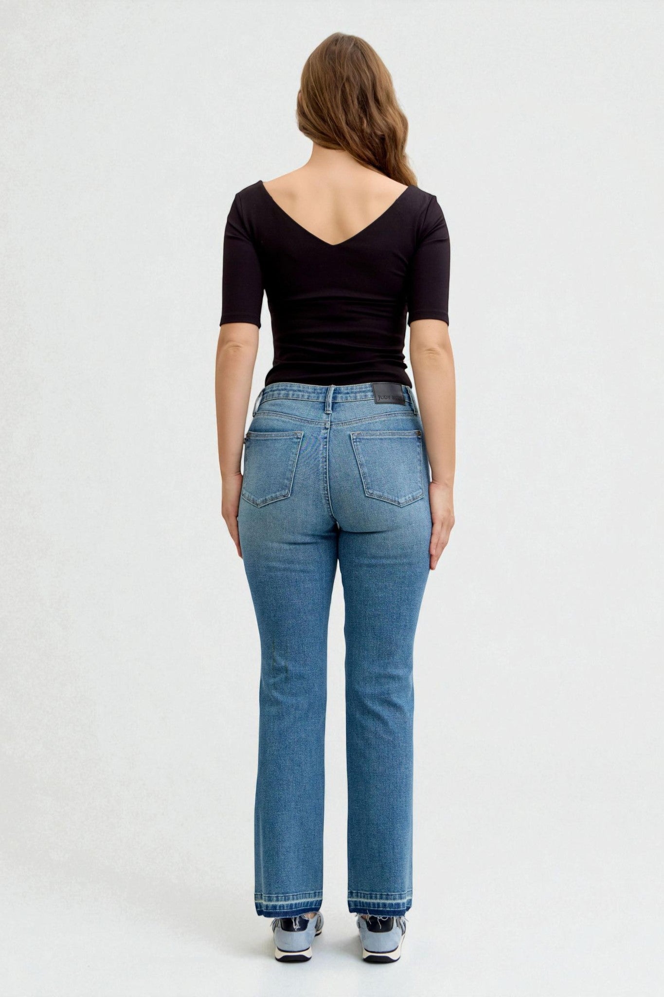 Person wearing blue jeans and a black top on a white background