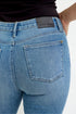 Close-up of blue jeans with a Judy Blue label on a white background