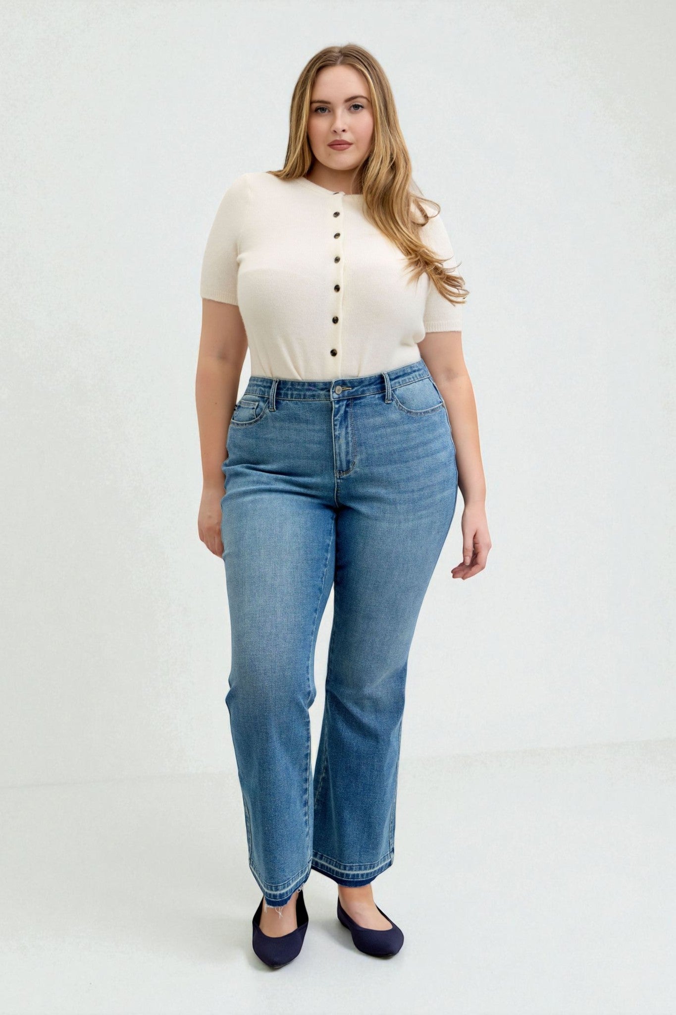 Woman wearing a cream top and blue jeans on a white background