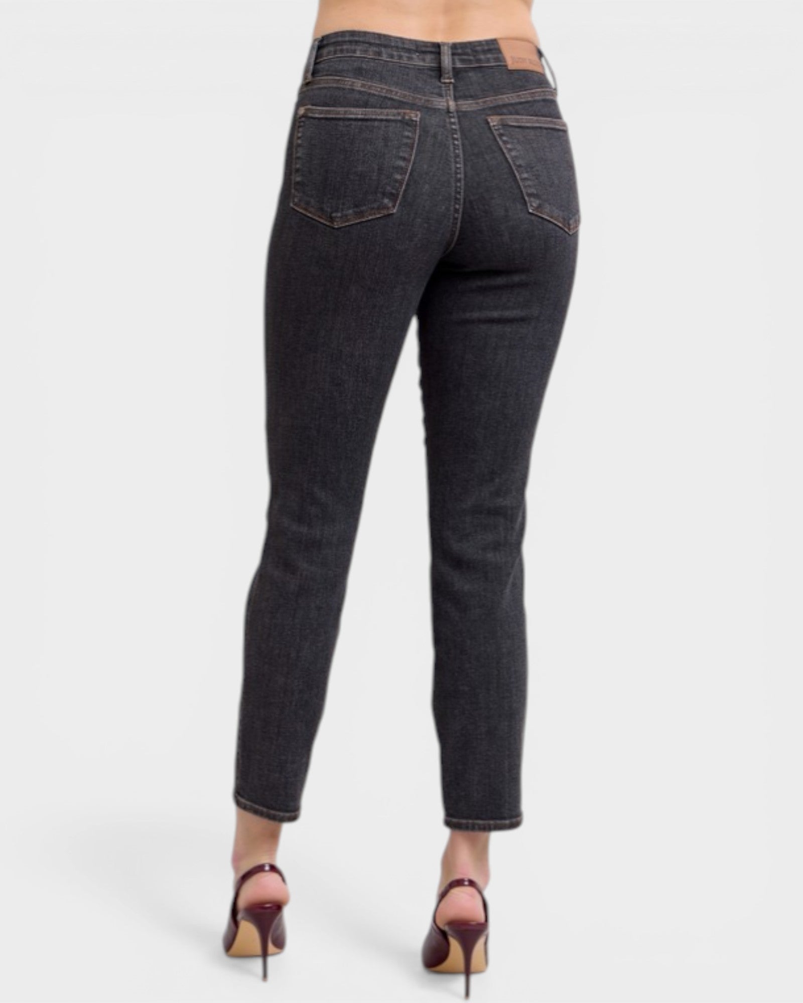 Dark blue jeans worn by a person on a white background