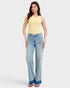 Woman wearing a yellow sleeveless top and light blue jeans on a white background