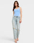 Woman wearing a light blue sleeveless top and distressed light blue jeans on a white background