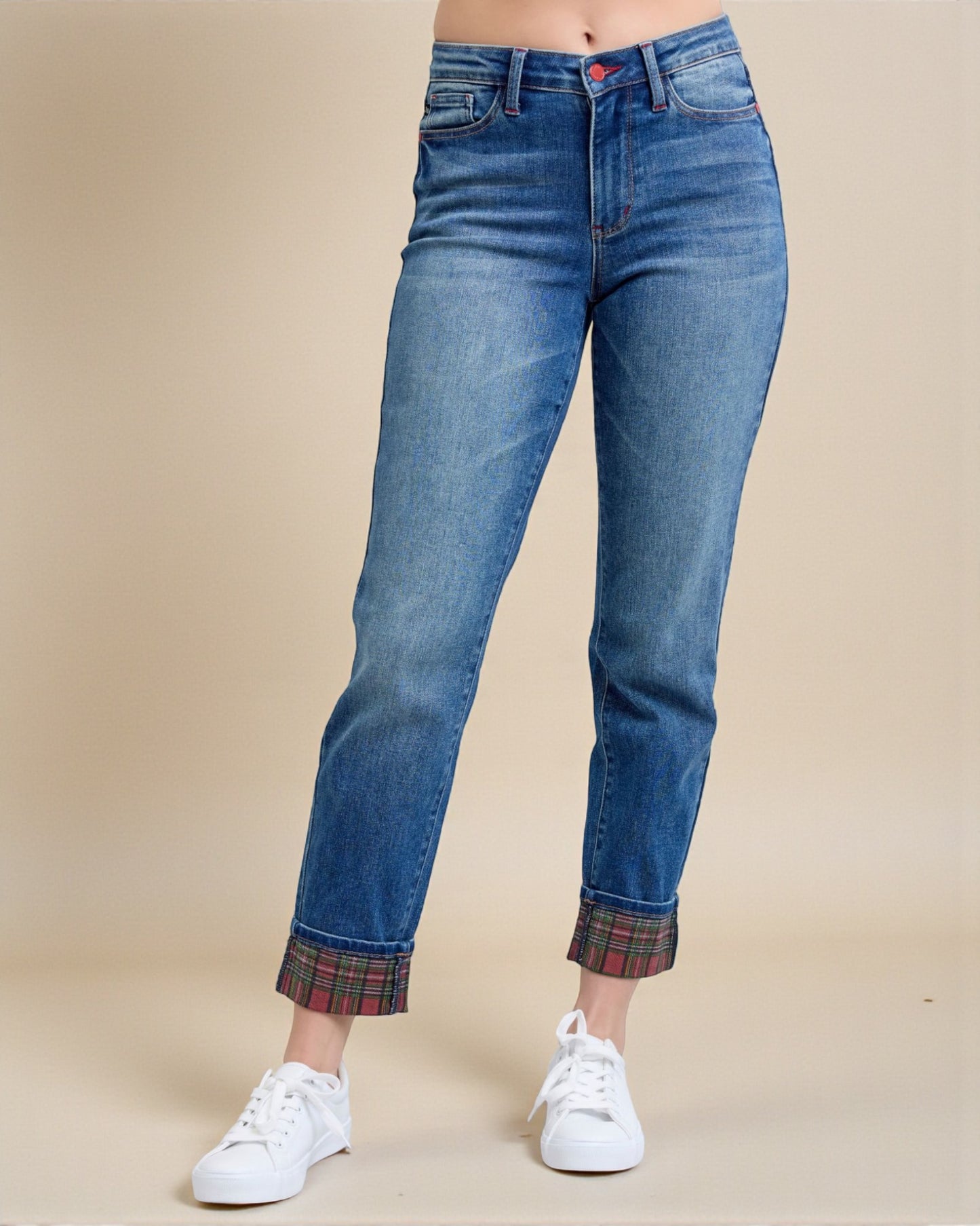Blue jeans with plaid cuffs worn by a person on a beige background