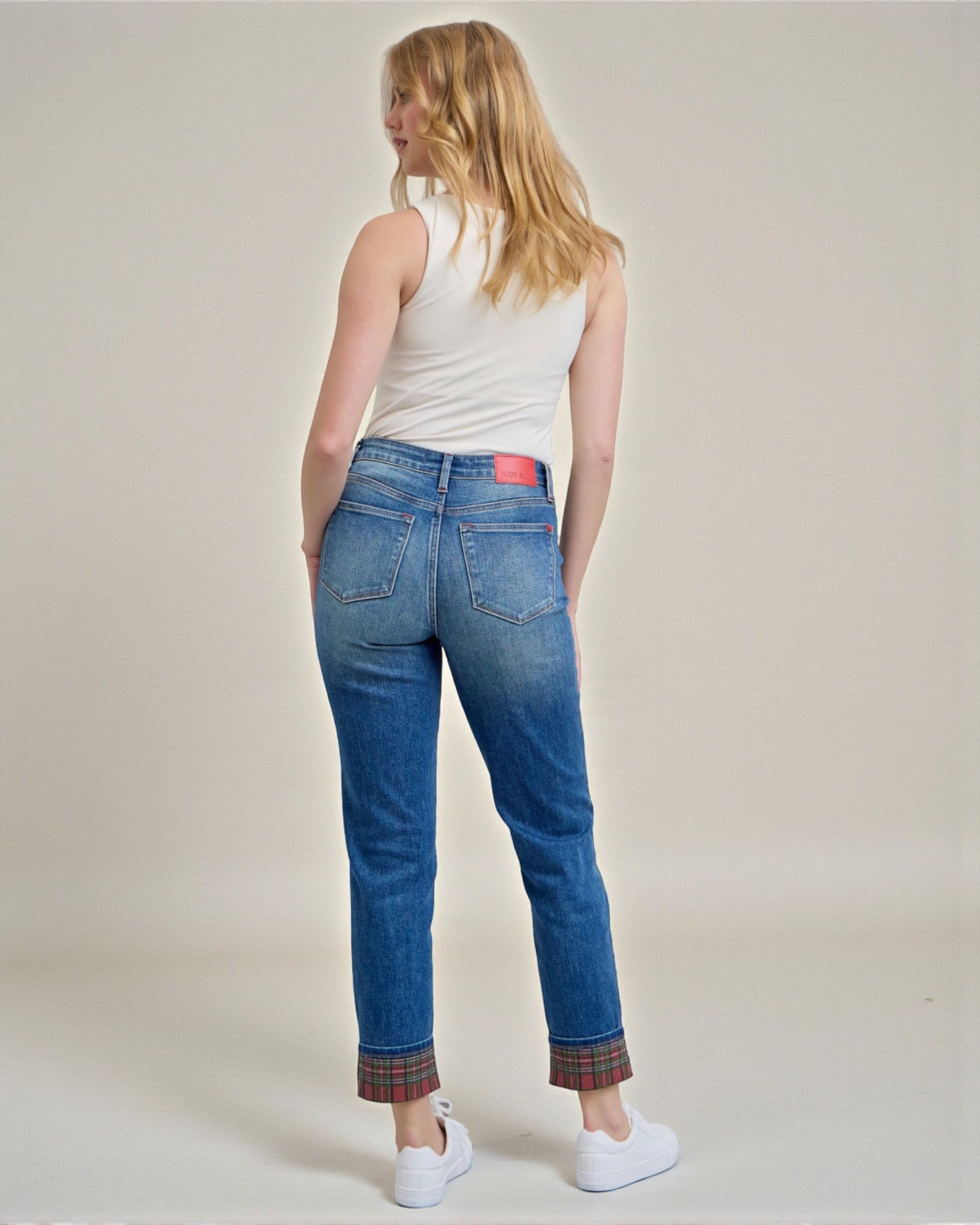 Woman wearing blue jeans with plaid cuffs on a plain background