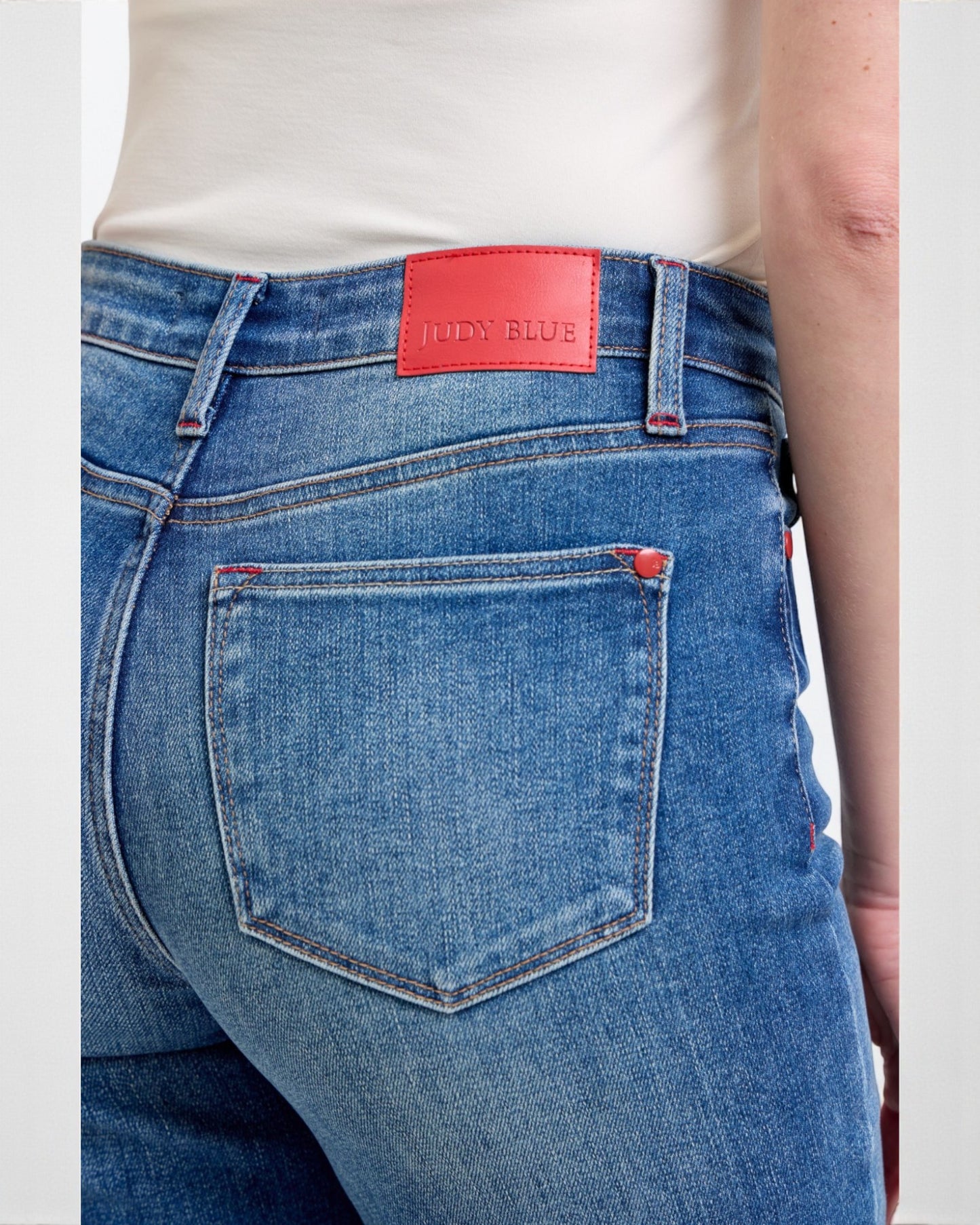 Close-up of blue jeans with a red tag on a white background