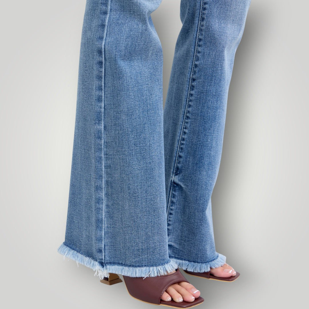 Blue jeans with frayed hem worn by a person on a light gray background